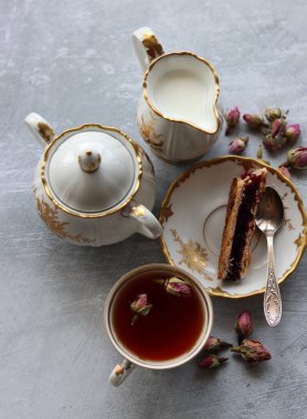 Bir fincan çay, bir sürahi süt, vişneli turta, küçük gül çiçekleri ile sakin bir hayat. Masadaki beyaz antika sofra takımı. Güzel kahvaltı. Yakın plan fotoğraf.. 