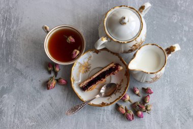 Güllü çay, yakın çekim fotoğrafı. Masadaki küçük beyaz seramik bardakta bitki çayı. Kopyalama alanı olan açık gri arkaplan. 