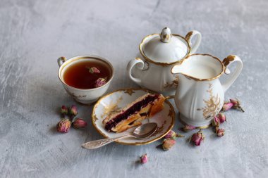 Bir fincan çay, bir sürahi süt, vişneli turta, küçük gül çiçekleri ile sakin bir hayat. Masadaki beyaz antika sofra takımı. Güzel kahvaltı. Yakın plan fotoğraf.. 