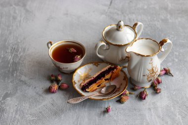 Bir fincan çay, bir sürahi süt, vişneli turta, küçük gül çiçekleri ile sakin bir hayat. Masadaki beyaz antika sofra takımı. Güzel kahvaltı. Yakın plan fotoğraf.. 