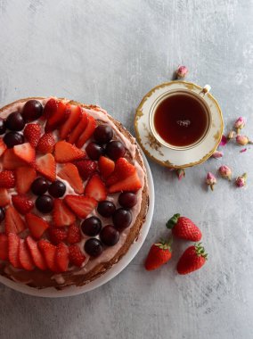 Pasta ve bir fincan siyah çayla sakin bir hayat. Çilekli pasta, yakın plan fotoğraf. Masanın üzerinde çok güzel eski moda masa takımı var. Doğum günü kutlaması fotoğrafı.  