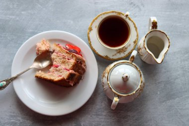 Bir parça çilekli kek ve bir fincan siyah çay. Kopyalama alanı olan açık gri arkaplan. Tatlı yemek. Yakın çekim.. 
