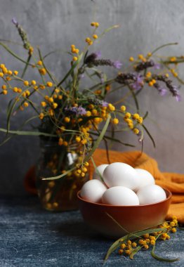 Basit kompozisyon Paskalya kartı. Güzel akasya ve lavanta çiçekleri kavanozda, yumurtalar seramik kasede. Kopyalama alanı olan açık gri arkaplan. 