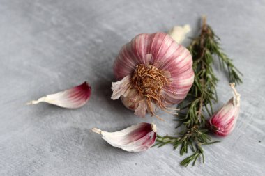 Sarımsak soğanı ve karanfil açık gri bir masada. Baharatların fotoğrafını kapat. Gıda hala hayat. 