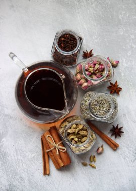 Çaydanlık ve cam kavanoz baharatlarla dolu sakin bir hayat. Siyah çay, karanfil, kakule. Tarçın, anason yıldızları ve lavanta rengi üst manzara fotoğrafı. Geleneksel baharatlı çay.. 
