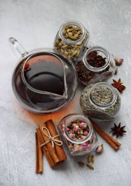 Çaydanlık ve cam kavanoz baharatlarla dolu sakin bir hayat. Siyah çay, karanfil, kakule. Tarçın, anason yıldızları ve lavanta rengi üst manzara fotoğrafı. Geleneksel baharatlı çay.. 