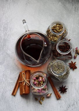 Çaydanlık ve baharatlar açık gri arka planda fotokopi alanı ile birlikte. Masadaki farklı çay çeşitleri. Lavanta, kakule, tarçın, gül, anason yıldızları ve karanfilli üstten görüntü.. 