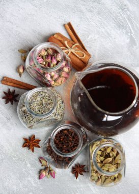 Çaydanlık ve cam kavanoz baharatlarla dolu sakin bir hayat. Siyah çay, karanfil, kakule. Tarçın, anason yıldızları ve lavanta rengi üst manzara fotoğrafı. Geleneksel baharatlı çay.. 