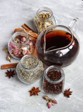 Çaydanlık ve cam kavanoz baharatlarla dolu sakin bir hayat. Siyah çay, karanfil, kakule. Tarçın, anason yıldızları ve lavanta rengi üst manzara fotoğrafı. Geleneksel baharatlı çay.. 