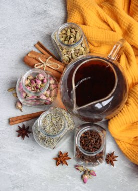 Çaydanlık ve cam kavanoz baharatlarla dolu sakin bir hayat. Siyah çay, karanfil, kakule. Tarçın, anason yıldızları ve lavanta rengi üst manzara fotoğrafı. Geleneksel baharatlı çay.. 