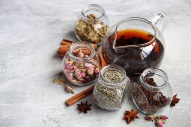 Çaydanlık ve cam kavanoz baharatlarla dolu sakin bir hayat. Siyah çay, karanfil, kakule. Tarçın, anason yıldızları ve lavanta rengi üst manzara fotoğrafı. Geleneksel baharatlı çay.. 