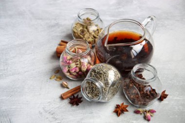 Çaydanlık ve baharatlar açık gri arka planda fotokopi alanı ile birlikte. Masadaki farklı çay çeşitleri. Lavanta, kakule, tarçın, gül, anason yıldızları ve karanfilli üstten görüntü.. 