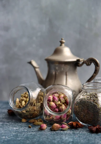 Çaydanlık ve cam kavanoz baharatlarla dolu sakin bir hayat. Siyah çay, karanfil, kakule. Tarçın, anason yıldızları ve lavanta rengi üst manzara fotoğrafı. Geleneksel baharatlı çay.. 