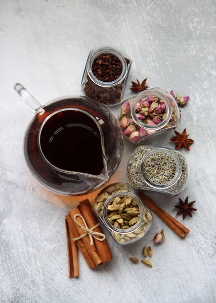 Çaydanlık ve cam kavanoz baharatlarla dolu sakin bir hayat. Siyah çay, karanfil, kakule. Tarçın, anason yıldızları ve lavanta rengi üst manzara fotoğrafı. Geleneksel baharatlı çay.. 