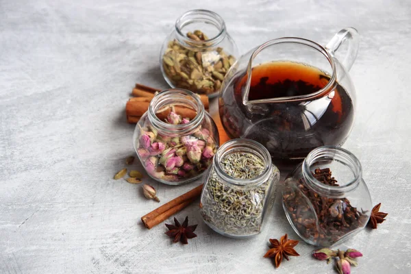 Çaydanlık ve cam kavanoz baharatlarla dolu sakin bir hayat. Siyah çay, karanfil, kakule. Tarçın, anason yıldızları ve lavanta rengi üst manzara fotoğrafı. Geleneksel baharatlı çay.. 