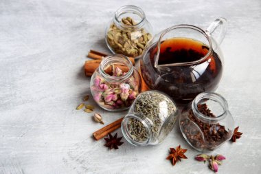 Still life with tea pot and glass jars of spices. Black tea, clove, cardamom. cinnamon, anise stars and lavender top view photo. Traditional spiced tea. 