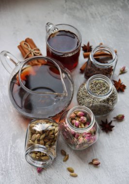 Çaydanlık ve baharatlar açık gri arka planda fotokopi alanı ile birlikte. Masadaki farklı çay çeşitleri. Lavanta, kakule, tarçın, gül, anason yıldızları ve karanfilli üstten görüntü.. 
