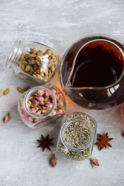 Çaydanlık ve baharatlar açık gri arka planda fotokopi alanı ile birlikte. Masadaki farklı çay çeşitleri. Lavanta, kakule, tarçın, gül, anason yıldızları ve karanfilli üstten görüntü.. 