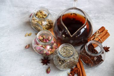 Çaydanlık ve baharatlar açık gri arka planda fotokopi alanı ile birlikte. Masadaki farklı çay çeşitleri. Lavanta, kakule, tarçın, gül, anason yıldızları ve karanfilli üstten görüntü.. 