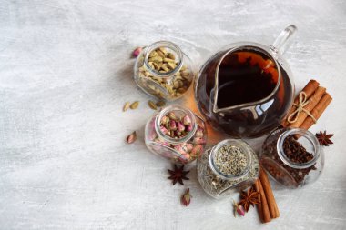 Çaydanlık ve baharatlar açık gri arka planda fotokopi alanı ile birlikte. Masadaki farklı çay çeşitleri. Lavanta, kakule, tarçın, gül, anason yıldızları ve karanfilli üstten görüntü.. 