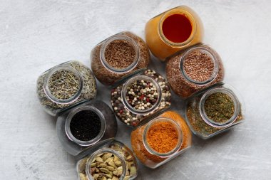 Cam kavanozlardaki farklı baharatlar. Yemek aromalarının yakın fotoğrafını çek. Kakule, zerdeçal, lavanta, köri, biber ve keten tohumu.. 