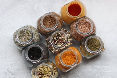 Cam kavanozlardaki farklı baharatlar. Yemek aromalarının yakın fotoğrafını çek. Kakule, zerdeçal, lavanta, köri, biber ve keten tohumu.. 