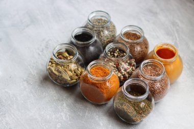Cam kavanozlardaki farklı baharatlar. Yemek aromalarının yakın fotoğrafını çek. Kakule, zerdeçal, lavanta, köri, biber ve keten tohumu.. 