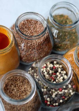 Cam kavanozlardaki farklı baharatlar. Yemek aromalarının yakın fotoğrafını çek. Kakule, zerdeçal, lavanta, köri, biber ve keten tohumu.. 