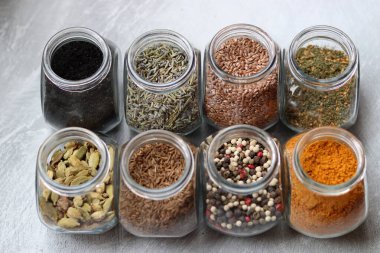 Cam kavanozlardaki farklı baharatlar. Yemek aromalarının yakın fotoğrafını çek. Kakule, zerdeçal, lavanta, köri, biber ve keten tohumu.. 