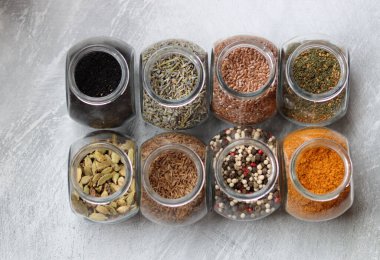 Cam kavanozlardaki farklı baharatlar. Yemek aromalarının yakın fotoğrafını çek. Kakule, zerdeçal, lavanta, köri, biber ve keten tohumu.. 