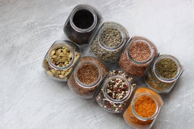 Cam kavanozlardaki farklı baharatlar. Yemek aromalarının yakın fotoğrafını çek. Kakule, zerdeçal, lavanta, köri, biber ve keten tohumu.. 