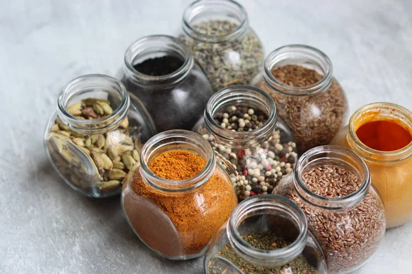 Cam kavanozlardaki farklı baharatlar. Yemek aromalarının yakın fotoğrafını çek. Kakule, zerdeçal, lavanta, köri, biber ve keten tohumu.. 