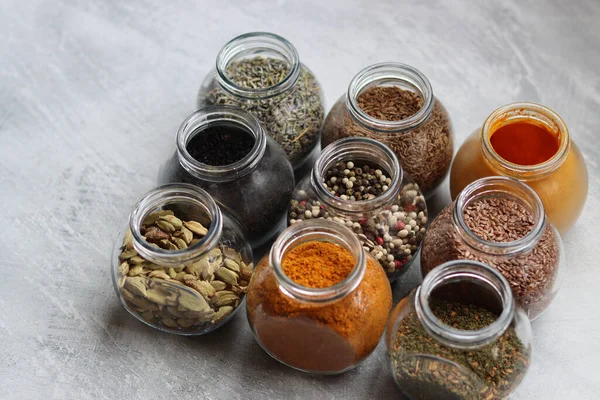 Cam kavanozlardaki farklı baharatlar. Yemek aromalarının yakın fotoğrafını çek. Kakule, zerdeçal, lavanta, köri, biber ve keten tohumu.. 