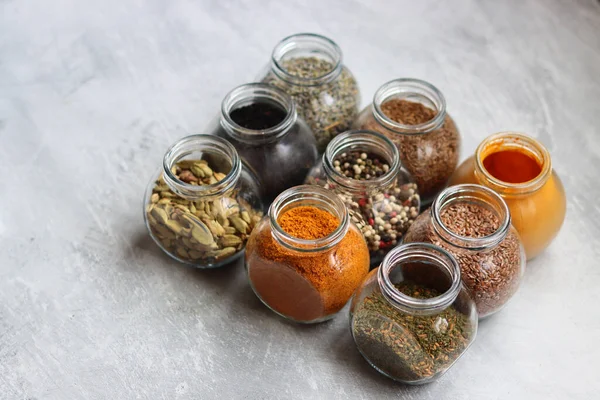 Cam kavanozlardaki farklı baharatlar. Yemek aromalarının yakın fotoğrafını çek. Kakule, zerdeçal, lavanta, köri, biber ve keten tohumu.. 