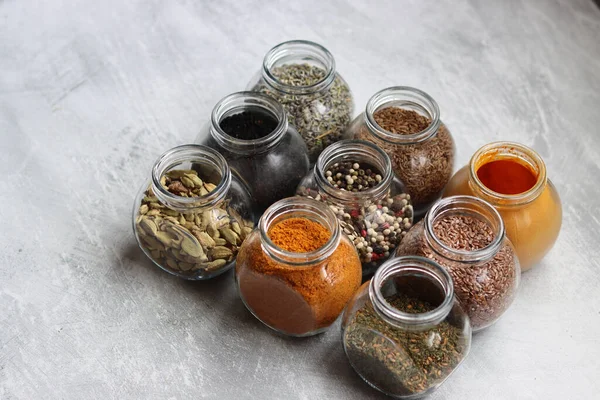 Cam kavanozlardaki farklı baharatlar. Yemek aromalarının yakın fotoğrafını çek. Kakule, zerdeçal, lavanta, köri, biber ve keten tohumu.. 