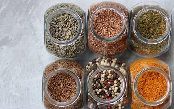 Cam kavanozlardaki farklı baharatlar. Yemek aromalarının yakın fotoğrafını çek. Kakule, zerdeçal, lavanta, köri, biber ve keten tohumu.. 