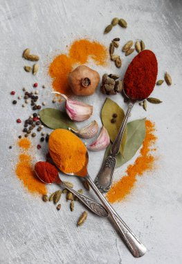 Gümüş kaşıklar, zerdeçal, paprika tozu, defne yaprağı ve biberli hayat. Hint baharatlarının canlı renkleri. Aromatik baharatlar ve bitkiler masada. Yiyecek çeşnileri dokusu yakın.. 