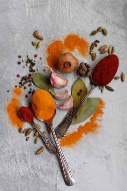 Gümüş kaşıklar, zerdeçal, paprika tozu, defne yaprağı ve biberli hayat. Hint baharatlarının canlı renkleri. Aromatik baharatlar ve bitkiler masada. Yiyecek çeşnileri dokusu yakın.. 