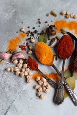 Baharatlı kaşıklar yakın çekim fotoğrafı. Zerdeçal, paprika tozu, bezelye, sarımsak, biber, masada defne yaprağı. Aromatik baharat ve bitkilerin renkli bir resmi. 