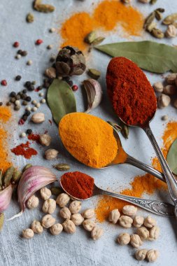 Baharatlı kaşıklar yakın çekim fotoğrafı. Zerdeçal, paprika tozu, bezelye, sarımsak, biber, masada defne yaprağı. Aromatik baharat ve bitkilerin renkli bir resmi. 