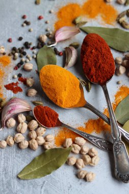 Gümüş kaşıklar, zerdeçal, paprika tozu, defne yaprağı ve biberli hayat. Hint baharatlarının canlı renkleri. Aromatik baharatlar ve bitkiler masada. Yiyecek çeşnileri dokusu yakın.. 