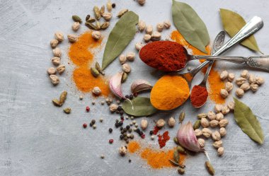 Hint baharatlı gümüş kaşıklar. Zerdeçal, kakule, paprika tozu, defne yaprağı ve açık gri zemin üzerinde fotokopi alanı olan sarımsak.. 