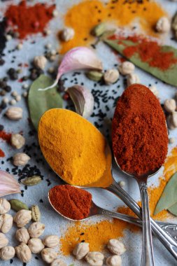 Gümüş kaşıklar, zerdeçal, paprika tozu, defne yaprağı ve biberli hayat. Hint baharatlarının canlı renkleri. Aromatik baharatlar ve bitkiler masada. Yiyecek çeşnileri dokusu yakın.. 