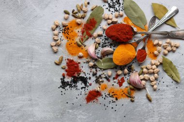 Hint baharatlı gümüş kaşıklar. Zerdeçal, kakule, paprika tozu, defne yaprağı ve açık gri zemin üzerinde fotokopi alanı olan sarımsak.. 