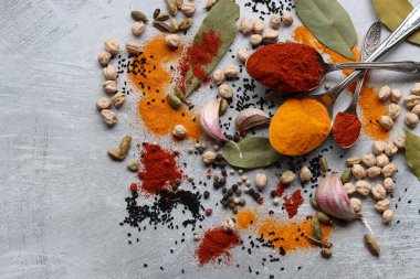 Hint baharatlı gümüş kaşıklar. Zerdeçal, kakule, paprika tozu, defne yaprağı ve açık gri zemin üzerinde fotokopi alanı olan sarımsak.. 