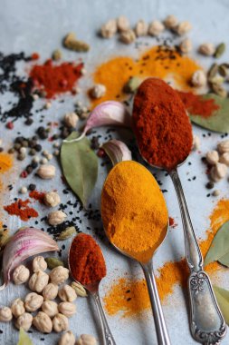 Baharatlı kaşıklar yakın çekim fotoğrafı. Zerdeçal, paprika tozu, bezelye, sarımsak, biber, masada defne yaprağı. Aromatik baharat ve bitkilerin renkli bir resmi. 