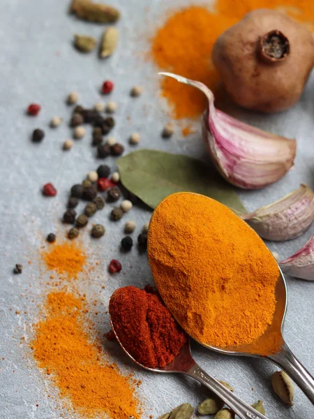 Baharatlı kaşıklar yakın çekim fotoğrafı. Zerdeçal, paprika tozu, bezelye, sarımsak, biber, masada defne yaprağı. Aromatik baharat ve bitkilerin renkli bir resmi. 