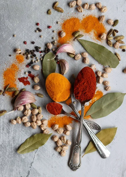 Gümüş kaşıklar, zerdeçal, paprika tozu, defne yaprağı ve biberli hayat. Hint baharatlarının canlı renkleri. Aromatik baharatlar ve bitkiler masada. Yiyecek çeşnileri dokusu yakın.. 