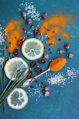 Değişik aromatik otlar ve baharatlar, canlı mavi arka planda. Kırmızı biber, zerdeçal tozu, sarımsak, karanfil, biber ve gülün renkli bir resmi. Doğal antioksidan kavramı. 