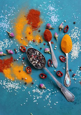 Değişik aromatik otlar ve baharatlar, canlı mavi arka planda. Kırmızı biber, zerdeçal tozu, sarımsak, karanfil, biber ve gülün renkli bir resmi. Doğal antioksidan kavramı. 